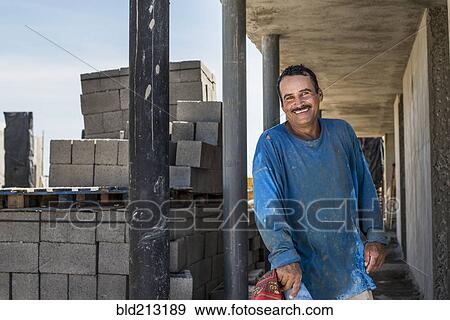 Stock Photo - Hispanic construction worker smiling at construction site. Fotosearch