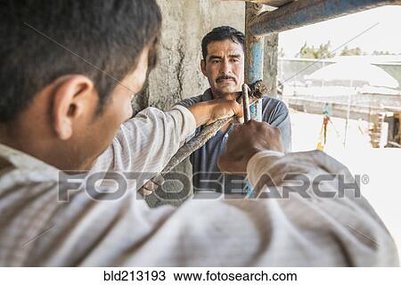 Stock Image - Hispanic construction workers with scaffolding at construction site. Fotosearch