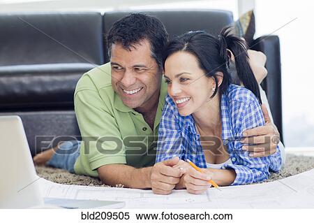 Hispanic couple examining blueprints in living room View Large Photo Image Stock Photography - Hispanic couple examining blueprints in living room. Fotosearch