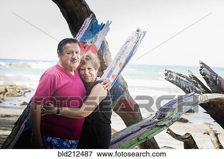 Stock Photo - Hispanic couple hugging on beach. Fotosearch