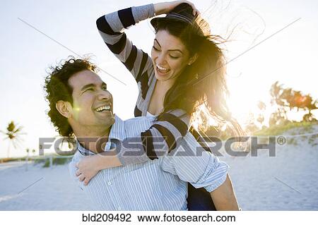 Stock Image - Hispanic couple playing on beach. Fotosearch