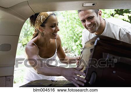 Stock Photograph - Hispanic couple putting suitcases in car. Fotosearch