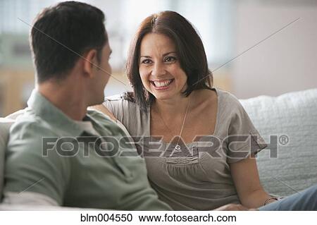 Stock Image - Hispanic couple talking on sofa. Fotosearch