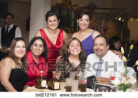 Stock Image - Hispanic family smiling at wedding reception. Fotosearch