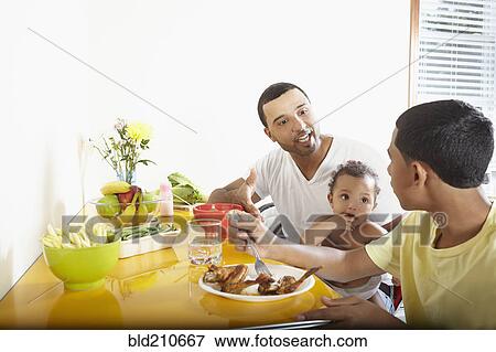 Stock Photo - Hispanic father and children eating together. Fotosearch