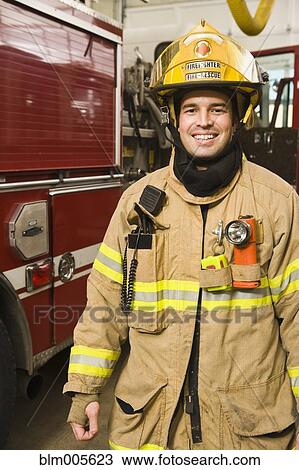 Stock Image - Hispanic fireman in coat and helmet. Fotosearch