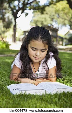 Hispanic girl laying in grass reading book View Large Photo Image Stock Photo - Hispanic girl laying in grass reading book. Fotosearch