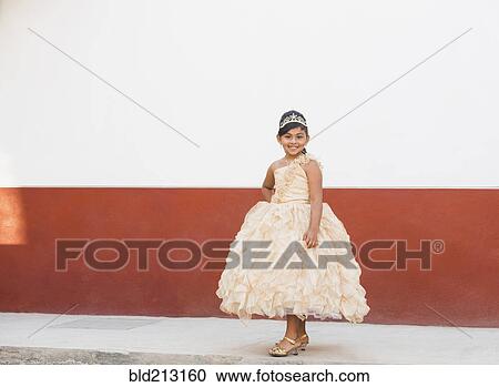 Stock Image - Hispanic girl posing in ornate gown and tiara. Fotosearch