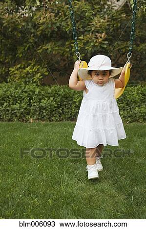 Stock Image - Hispanic girl swinging on swing. Fotosearch