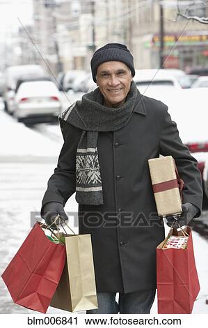 Stock Image - Hispanic man carrying christmas gifts. Fotosearch