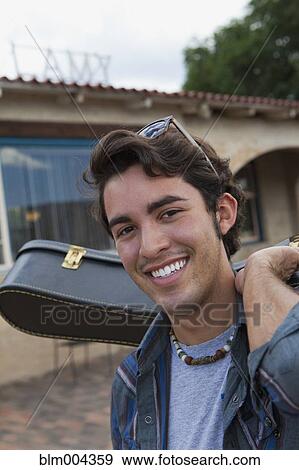 Stock Photo - Hispanic man carrying guitar case. Fotosearch