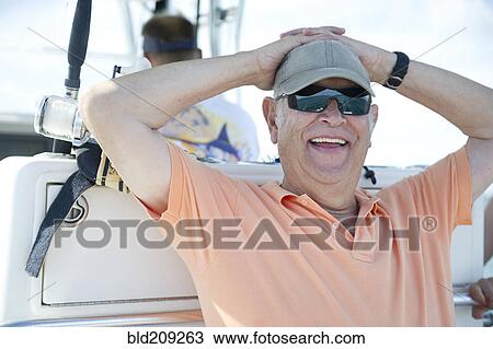 Stock Image - Hispanic man fishing in boat. Fotosearch
