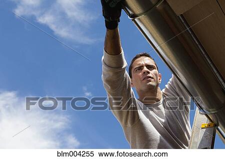 Hispanic man installing gutter on house View Large Photo Image Stock Photography - Hispanic man installing gutter on house. Fotosearch