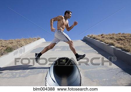 Hispanic man jumping over culvert View Large Photo Image Stock Photo - Hispanic man jumping over culvert. Fotosearch