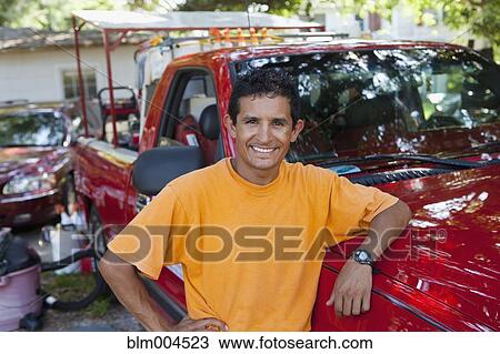 Stock Image - Hispanic man leaning on truck. Fotosearch