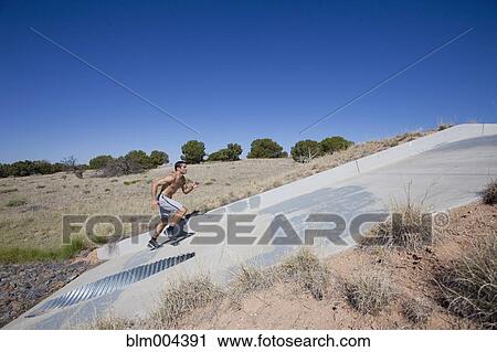 Hispanic man running up slope of culvert View Large Photo Image Stock Image - Hispanic man running up slope of culvert. Fotosearch