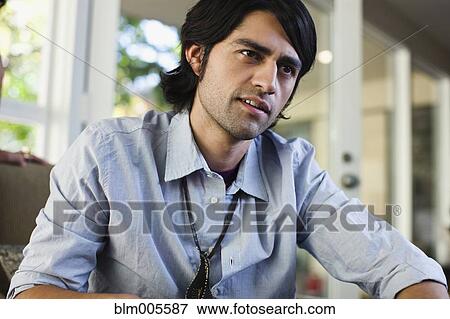 Stock Photo - Hispanic man sitting indoors. Fotosearch