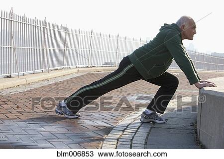 Stock Image - Hispanic man stretching in urban setting. Fotosearch