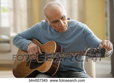 Stock Photography - Hispanic man tuning guitar. Fotosearch