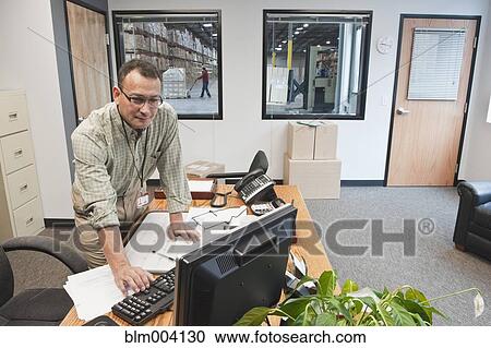 Hispanic man using computer in warehouse office View Large Photo Image Stock Image - Hispanic man using computer in warehouse office. Fotosearch