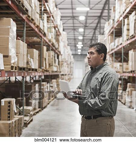 Hispanic man using laptop in warehouse View Large Photo Image Stock Image - Hispanic man using laptop in warehouse. Fotosearch
