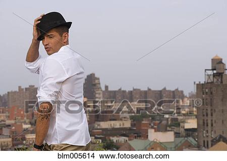 Hispanic man with tattoo wearing fedora on urban rooftop View Large Photo Image Picture - Hispanic man with tattoo wearing fedora on urban rooftop. Fotosearch