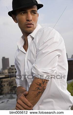 Stock Image - Hispanic man with tattoo wearing fedora. Fotosearch