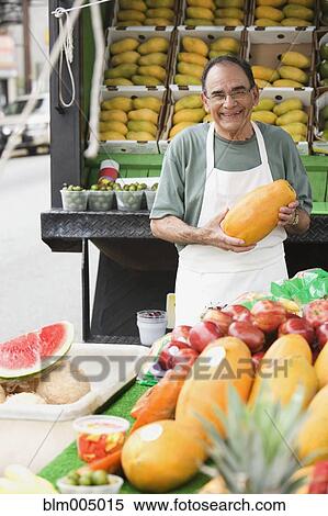 Stock Photography - Hispanic man working at fruit stall. Fotosearch
