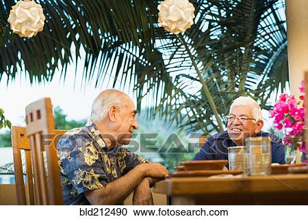 Stock Image - Hispanic men eating together in restaurant. Fotosearch