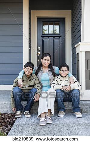 Stock Photo - Hispanic mother and sons sitting on front stoop. Fotosearch