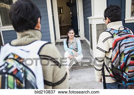Stock Photo - Hispanic mother greeting sons at door. Fotosearch