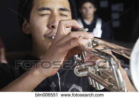 Stock Image - Hispanic student playing trumpet. Fotosearch