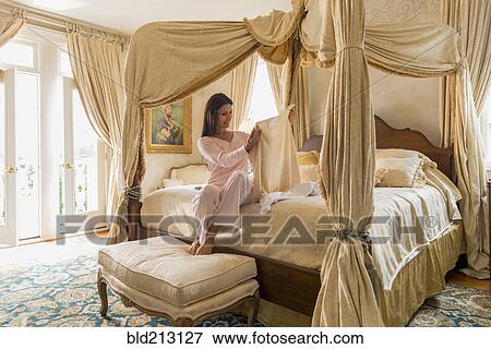 Stock Photo - Hispanic woman admiring clothes on bed. Fotosearch