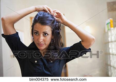 Hispanic woman fixing hair in bathroom View Large Photo Image Stock Photography - Hispanic woman fixing hair in bathroom. Fotosearch