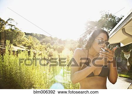 Hispanic woman in bikini lighting cigarette View Large Photo Image Stock Image - Hispanic woman in bikini lighting cigarette. Fotosearch