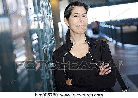 Stock Image - Hispanic woman leaning against lockers. Fotosearch