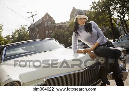 Hispanic woman leaning on hood of car View Large Photo Image Stock Image - Hispanic woman leaning on hood of car. Fotosearch