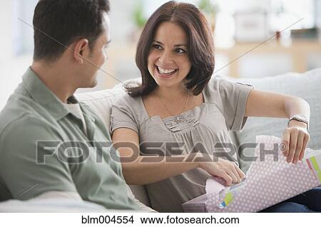 Picture - Hispanic woman opening gift from husband. Fotosearch