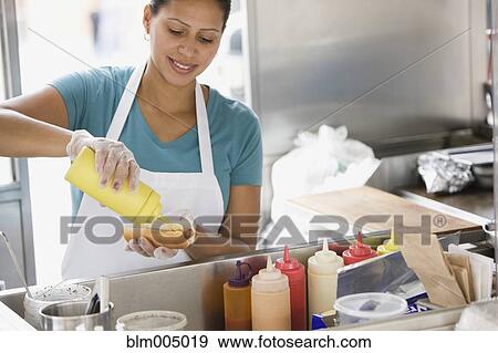 Hispanic woman preparing hot dog in food cart View Large Photo Image Stock Photo - Hispanic woman preparing hot dog in food cart. Fotosearch