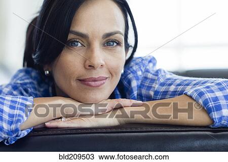 Stock Image - Hispanic woman relaxing on sofa. Fotosearch