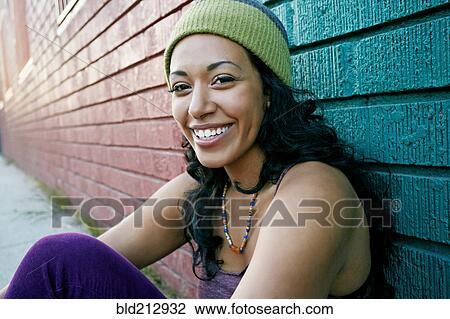 Stock Image - Hispanic woman sitting on city street. Fotosearch