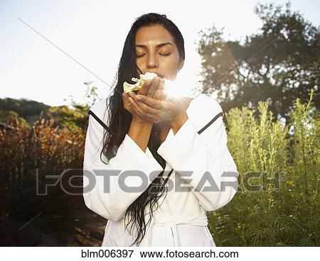 Stock Photo - Hispanic woman smelling Gardenia flower. Fotosearch
