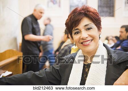 Stock Image - Hispanic woman smiling in church. Fotosearch