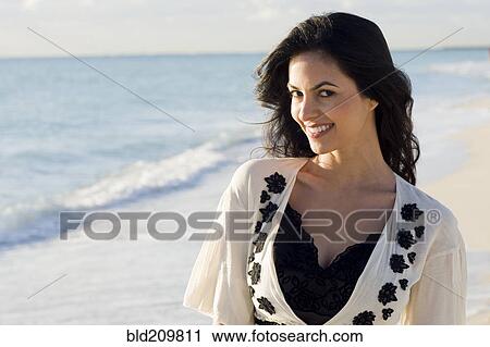 Stock Image - Hispanic woman smiling on beach. Fotosearch