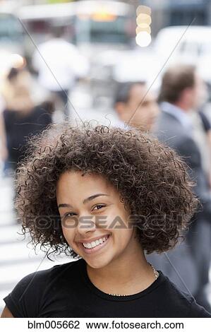Stock Image - Hispanic woman smiling on urban street. Fotosearch