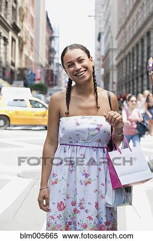 Stock Photography - Hispanic woman smiling on urban street. Fotosearch