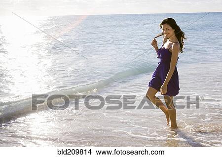 Hispanic woman walking in surf on beach View Large Photo Image Picture - Hispanic woman walking in surf on beach. Fotosearch