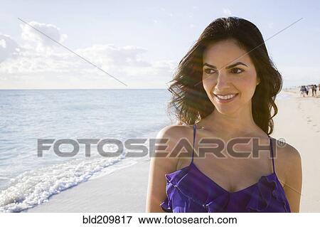 Stock Photo - Hispanic woman walking on beach. Fotosearch