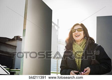 Stock Image - Hispanic woman walking on city street. Fotosearch