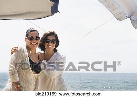 Stock Photo - Hispanic women smiling together at beach. Fotosearch